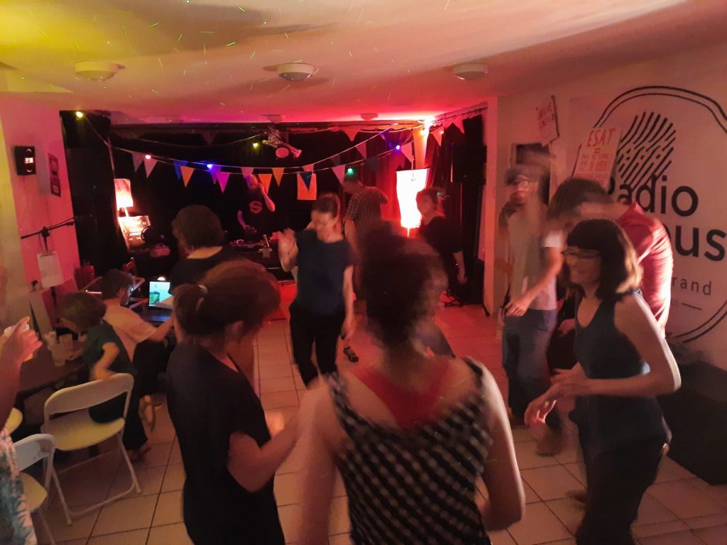 Des gens qui dansent dans une salle décorée de fanions et de lumières colorées